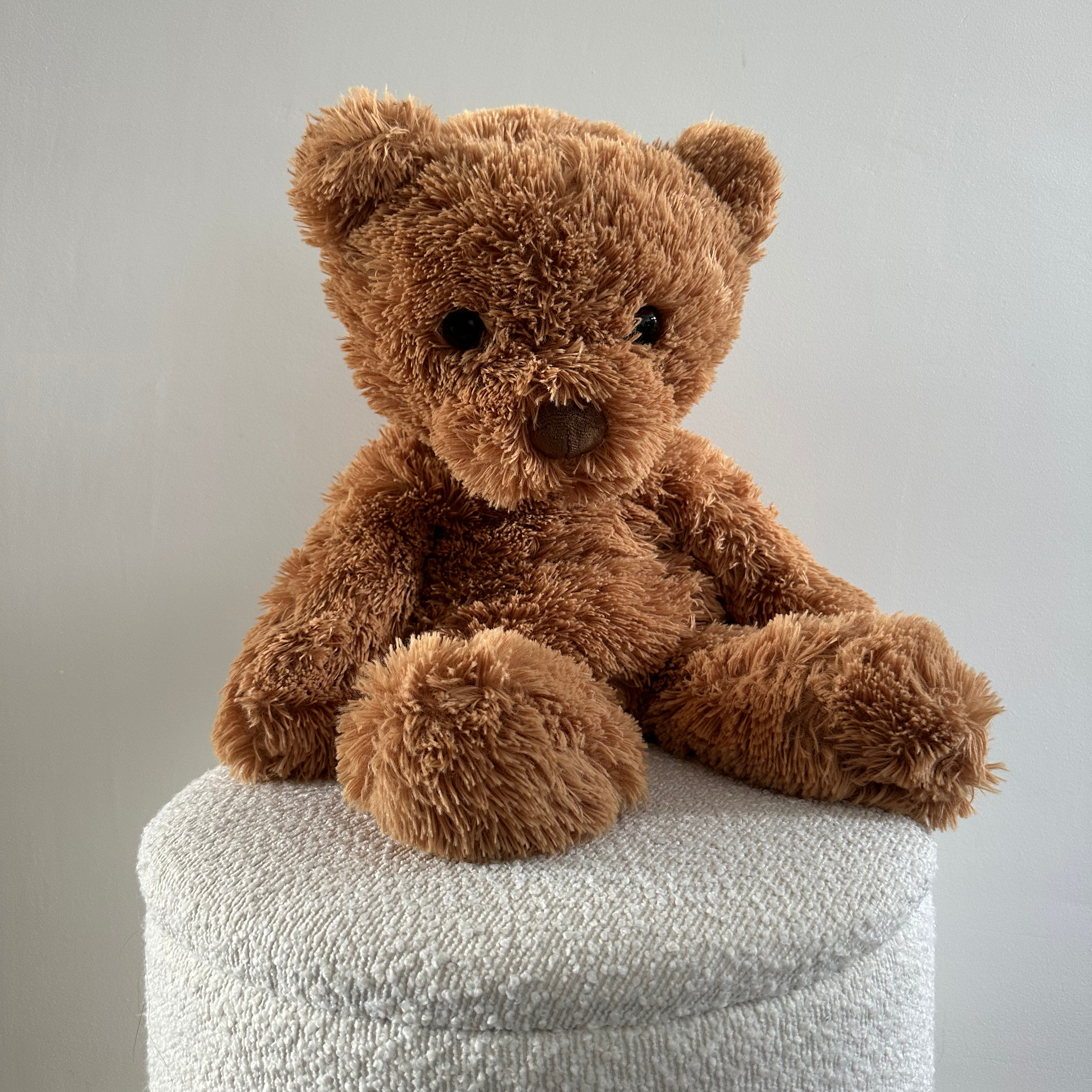 Verzwaringsknuffel Teddy zit op een poef