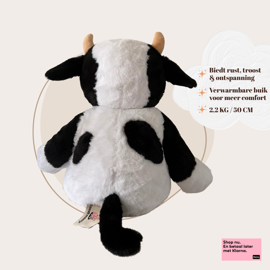 Achterkant van de verzwaarde koe knuffel met focus op de staart en het vlekkenpatroon van de pluche stof.